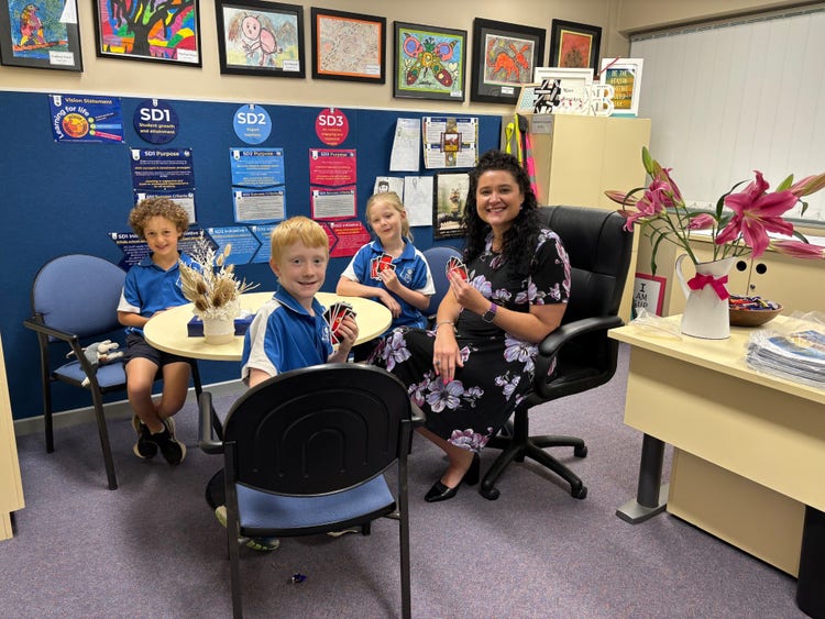 School Principal, Jessica Brooker playing cards with some students in her office