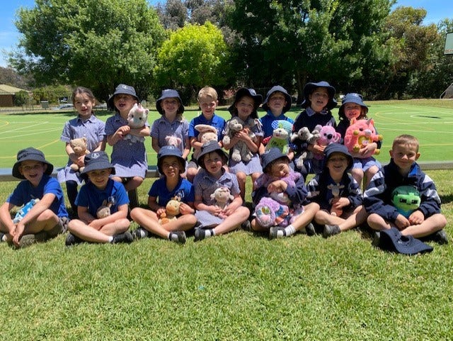 Kindergarten students with their teddy bears posing for a photo in the playground