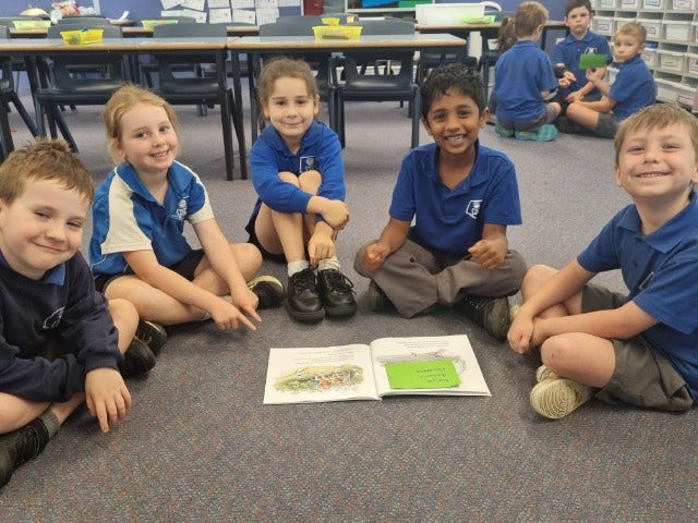 Students sitting on the classroom floor reading a book together