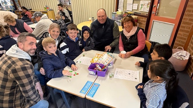 Families visiting classrooms during Education Week sitting around classroom desk