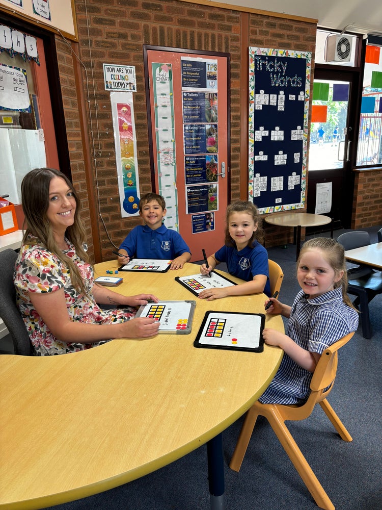 Class teacher assisting students in the classroom sitting around a classroom table