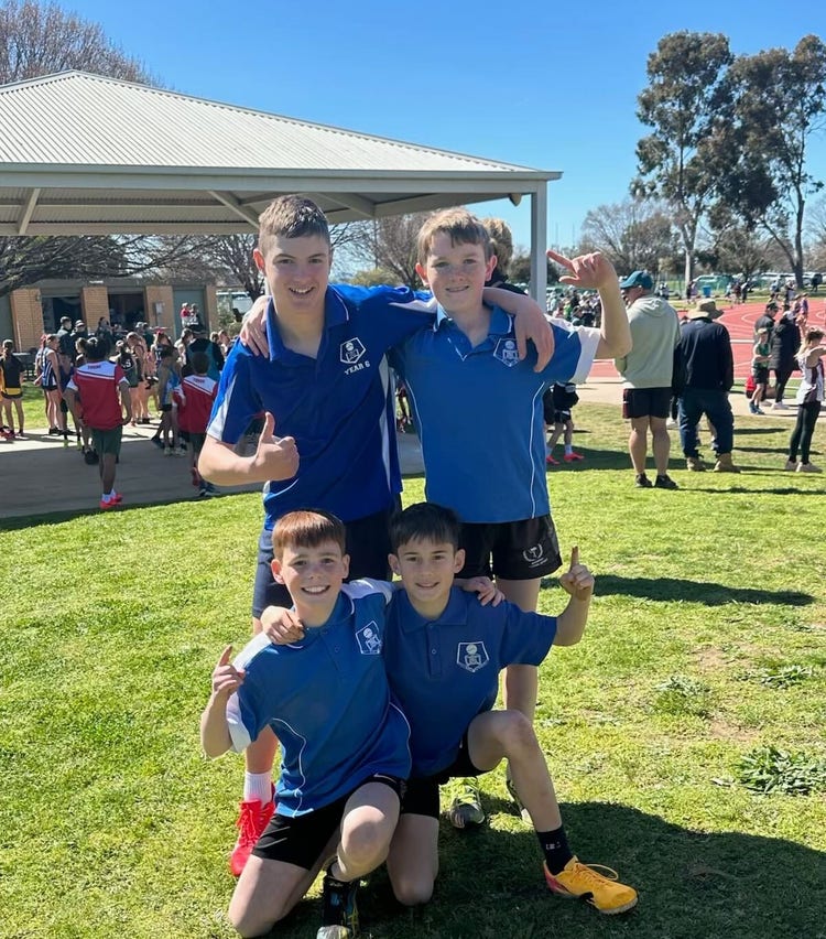 Four children embracing after winning the relay race at the sports carnival