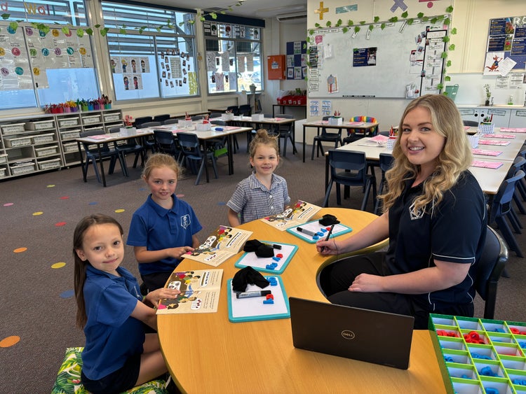 Teacher assisting students in class sitting around a table