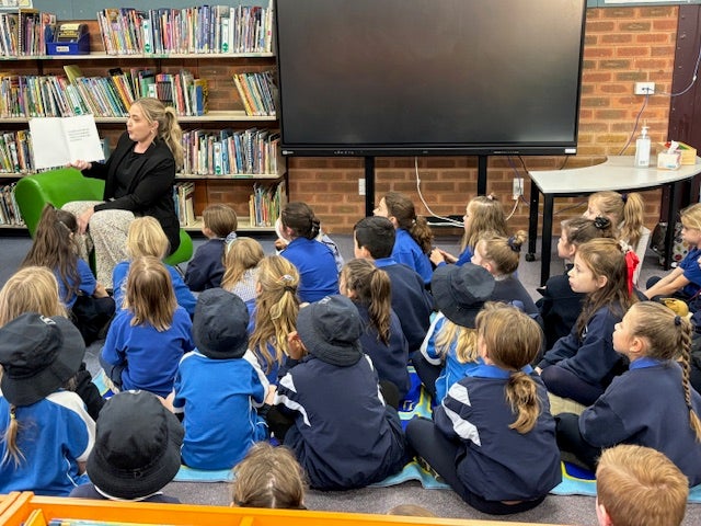 Teacher reading to a group of students in class